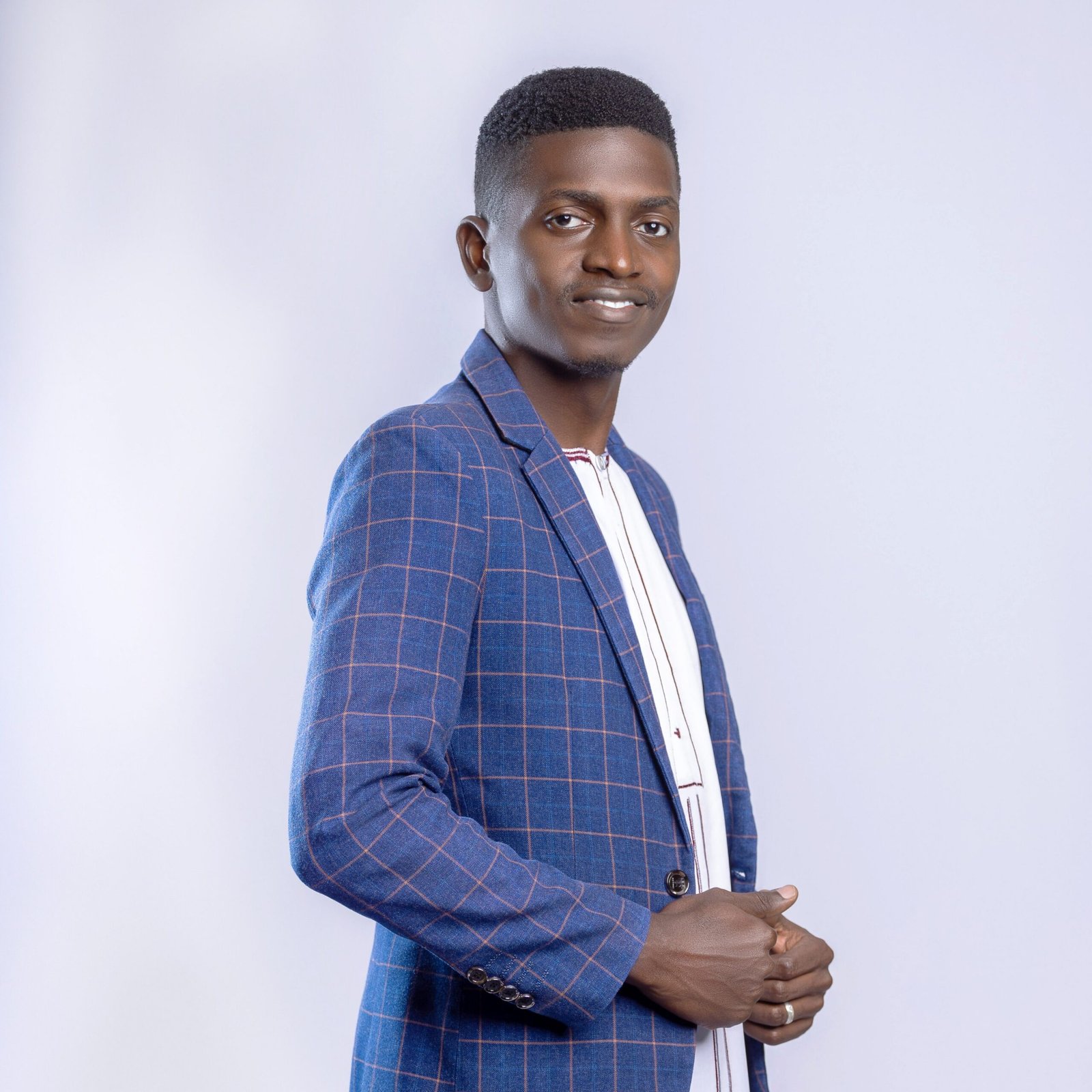 Stylish portrait of a confident young man in a blue checked suit against a neutral background.